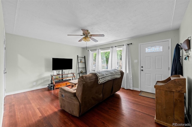 living area featuring a textured ceiling, ceiling fan, wood finished floors, and baseboards