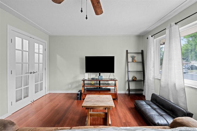 living room featuring ceiling fan, baseboards, and wood finished floors