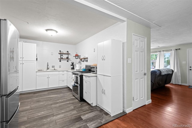 kitchen with stainless steel appliances, light countertops, dark wood-type flooring, white cabinets, and a sink