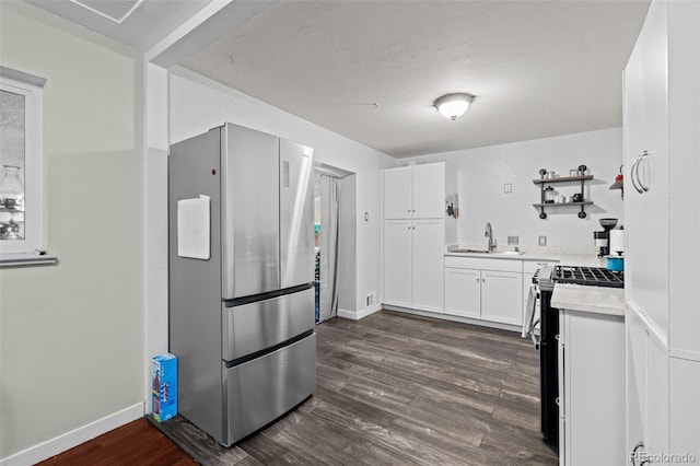 kitchen featuring dark wood-type flooring, stainless steel appliances, light countertops, white cabinetry, and a sink