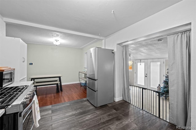 kitchen with french doors, stainless steel appliances, dark wood-type flooring, a textured ceiling, and baseboards