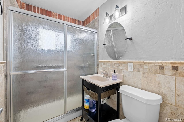 full bath featuring a textured wall, toilet, a sink, tile walls, and a stall shower