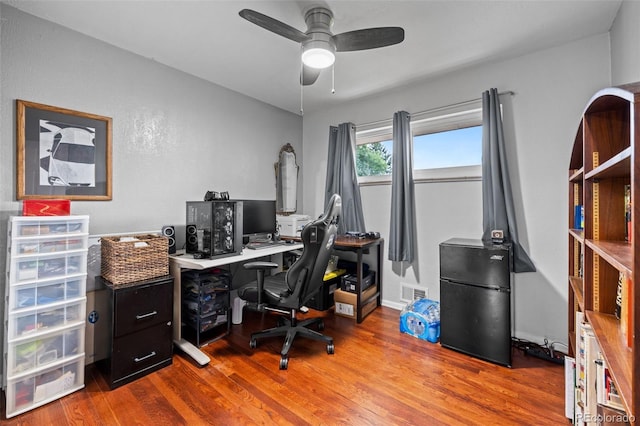 office area with wood finished floors, visible vents, and a ceiling fan