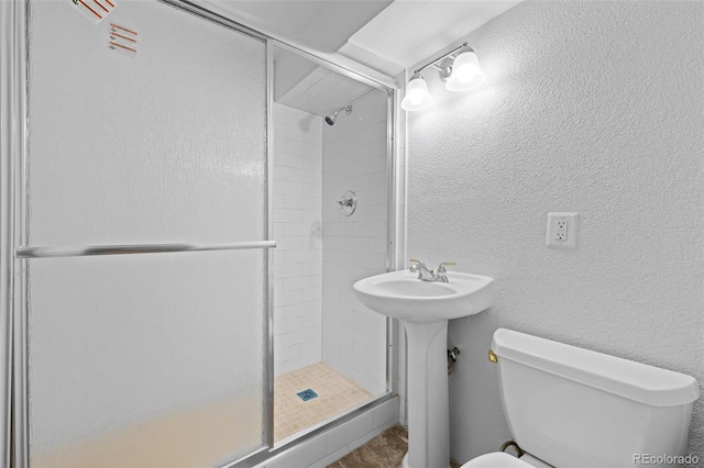 bathroom featuring a textured wall, a shower stall, and toilet