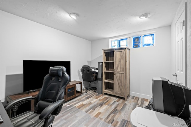 home office with light wood-style flooring and baseboards