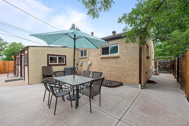 view of patio with fence, outdoor dining area, and central AC