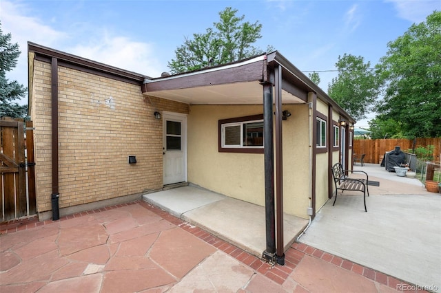 back of property with brick siding, stucco siding, fence, and a patio