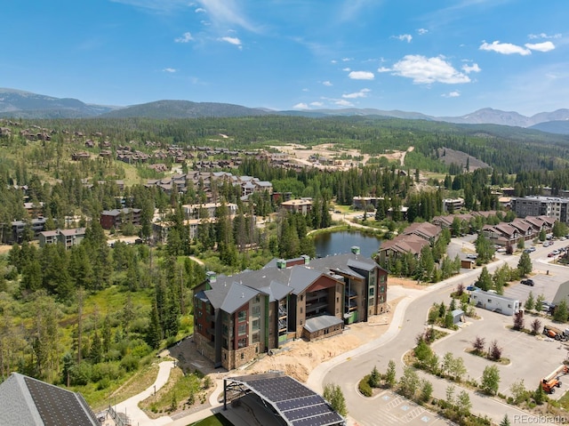 aerial view featuring a wooded view and a water and mountain view