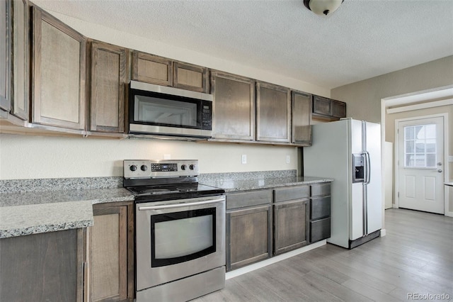 kitchen featuring a textured ceiling, light hardwood / wood-style flooring, dark brown cabinets, and stainless steel appliances