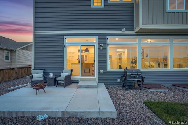 patio terrace at dusk featuring a fire pit and grilling area