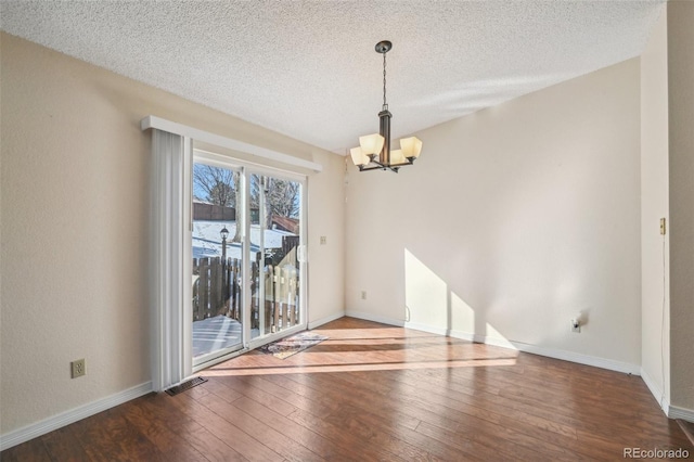 unfurnished room featuring a chandelier, hardwood / wood-style floors, and a textured ceiling