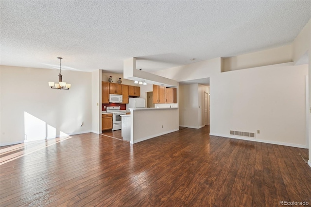 unfurnished living room featuring an inviting chandelier, a textured ceiling, and dark hardwood / wood-style flooring