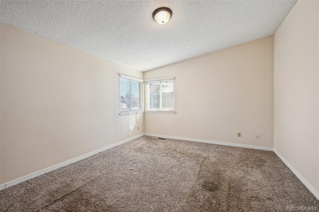 carpeted empty room featuring a textured ceiling