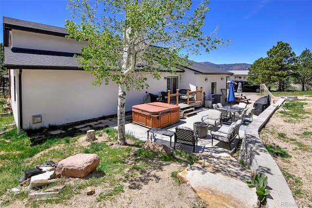 1673 Woodmoor Dr, Monument, CO 80132 - back of property featuring outdoor lounge area, stucco siding, a hot tub, a patio, and a deck