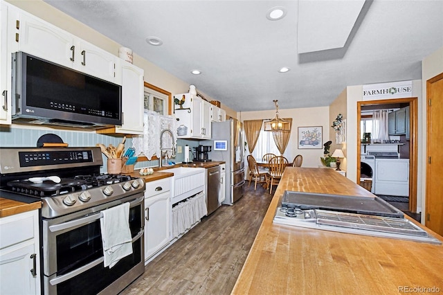 1673 Woodmoor Dr, Monument, CO 80132 - kitchen with stainless steel appliances, butcher block counters, washer and clothes dryer, white cabinetry, and recessed lighting