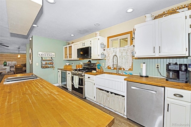 1673 Woodmoor Dr, Monument, CO 80132 - kitchen featuring appliances with stainless steel finishes, butcher block countertops, white cabinets, wood finished floors, and recessed lighting