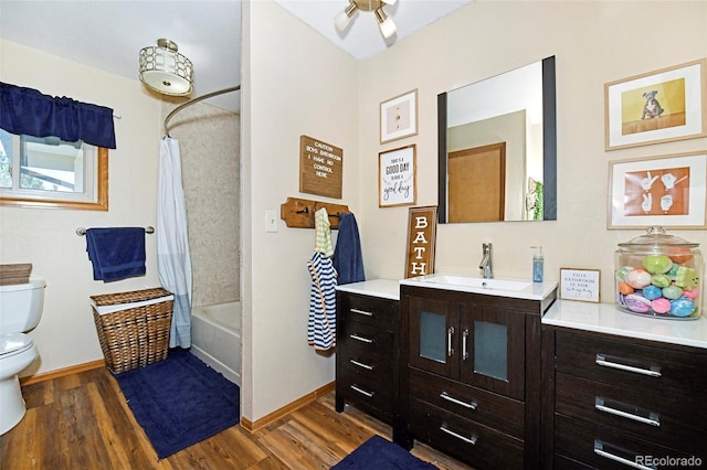 1673 Woodmoor Dr, Monument, CO 80132 - bathroom with wood finished floors, toilet, baseboards, vanity, and shower / bathtub combination with curtain