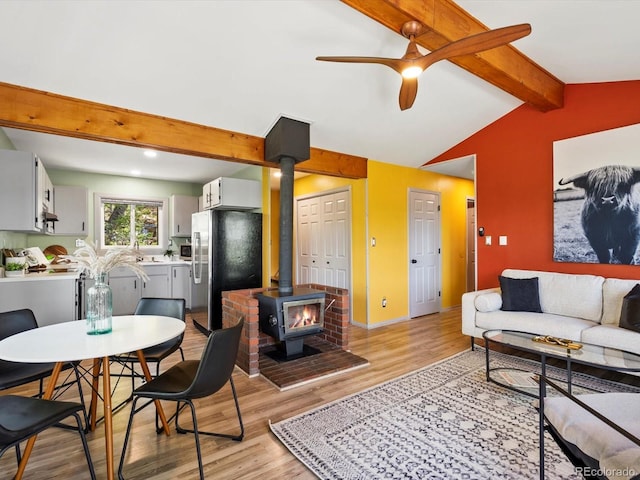11650 Baca Rd, Conifer, CO 80433 - living room featuring a wood stove, light wood-style flooring, a ceiling fan, and baseboards