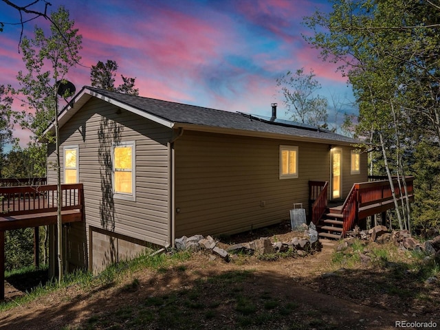 11650 Baca Rd, Conifer, CO 80433 - back of property at dusk featuring a deck, solar panels, and roof with shingles