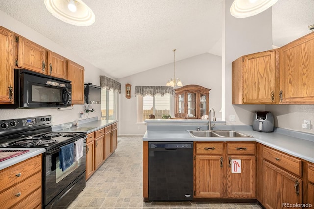 kitchen featuring light countertops, vaulted ceiling, a peninsula, black appliances, and a sink