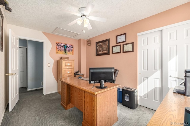 office featuring a textured ceiling, carpet flooring, baseboards, attic access, and ceiling fan