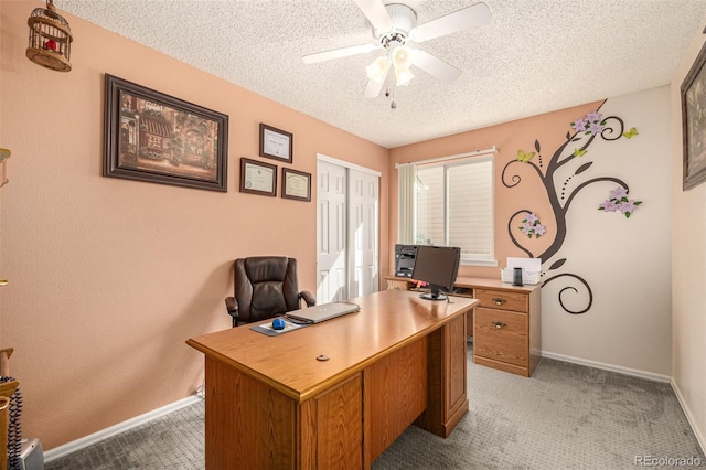 office area with baseboards, light colored carpet, ceiling fan, and a textured ceiling