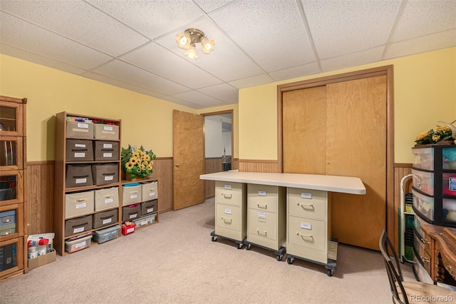 office space with a drop ceiling, a wainscoted wall, light carpet, and wood walls