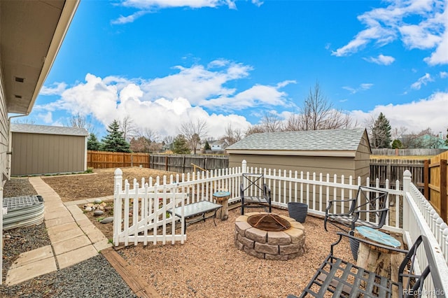 view of yard with an outbuilding, a storage unit, a fenced backyard, and an outdoor fire pit