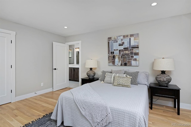 bedroom with ensuite bathroom and light hardwood / wood-style flooring