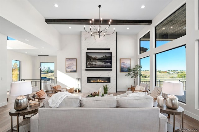 living room featuring beam ceiling, hardwood / wood-style flooring, an inviting chandelier, and a high end fireplace