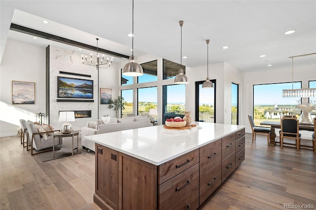 kitchen with a notable chandelier, wood-type flooring, a high end fireplace, and hanging light fixtures