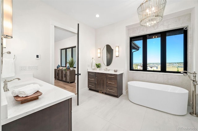 bathroom featuring vanity, a notable chandelier, a bath, and tile patterned flooring