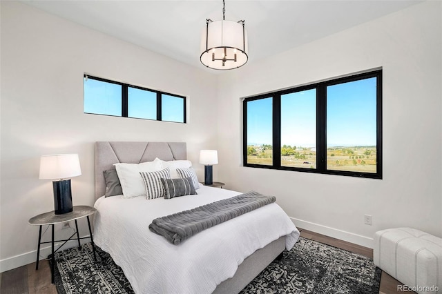 bedroom featuring an inviting chandelier and dark hardwood / wood-style flooring