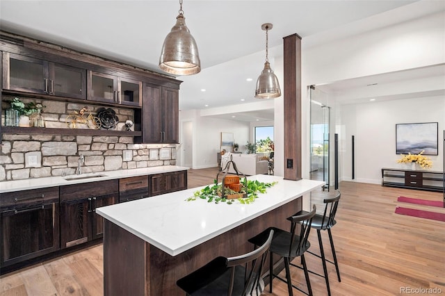 kitchen with dark brown cabinetry, sink, a kitchen bar, and light hardwood / wood-style floors