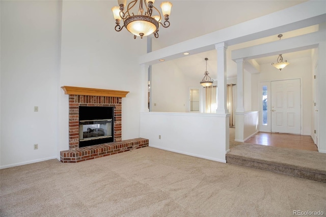 unfurnished living room featuring a brick fireplace, decorative columns, and carpet flooring