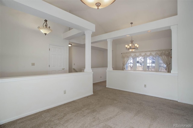 spare room featuring lofted ceiling, a notable chandelier, ornate columns, and carpet flooring