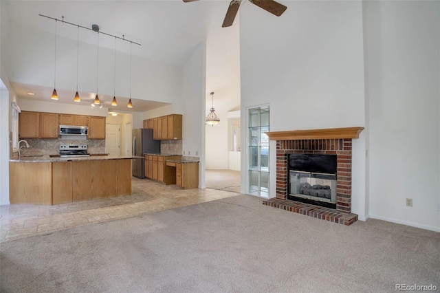 kitchen featuring sink, light colored carpet, kitchen peninsula, and appliances with stainless steel finishes