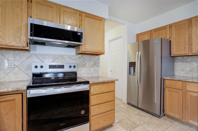 kitchen with light stone counters, backsplash, light tile patterned floors, and stainless steel appliances