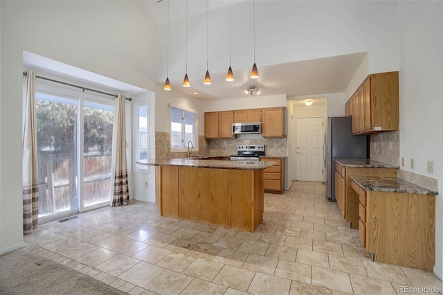 kitchen with appliances with stainless steel finishes, decorative light fixtures, sink, backsplash, and a high ceiling