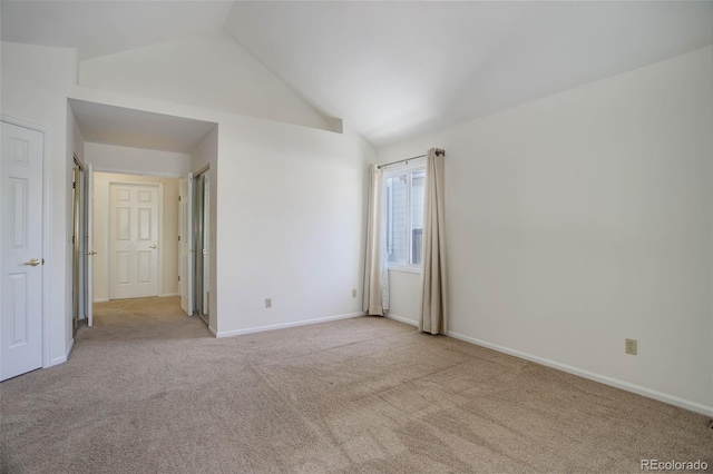 carpeted spare room with vaulted ceiling