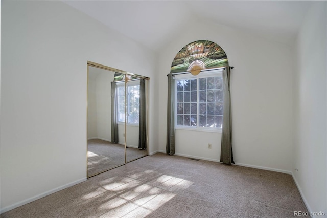 unfurnished bedroom with vaulted ceiling, light carpet, and a closet