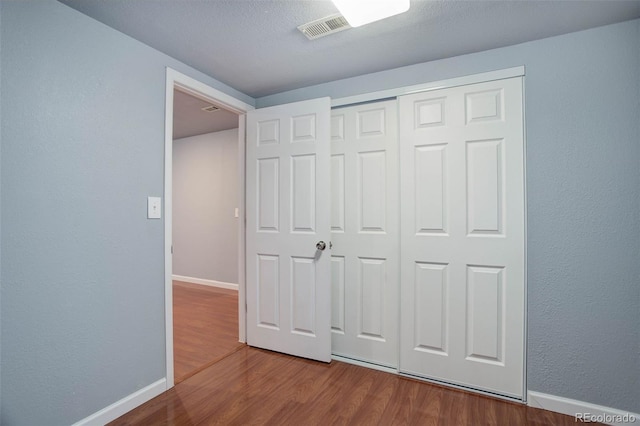 unfurnished bedroom with hardwood / wood-style flooring, a closet, and a textured ceiling