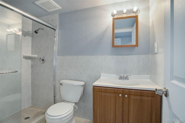 bathroom featuring walk in shower, vanity, toilet, and tile walls