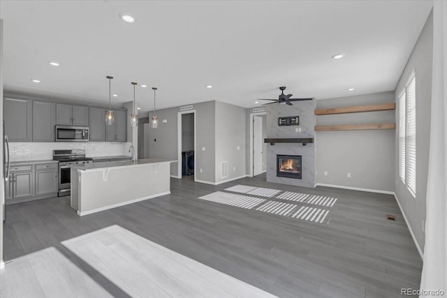 12862 Crane River Dr, Longmont, CO 80504 - kitchen featuring stainless steel appliances, ceiling fan, gray cabinetry, dark wood-style floors, and open floor plan