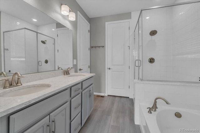 12862 Crane River Dr, Longmont, CO 80504 - bathroom featuring a stall shower, double vanity, a garden tub, and wood finished floors