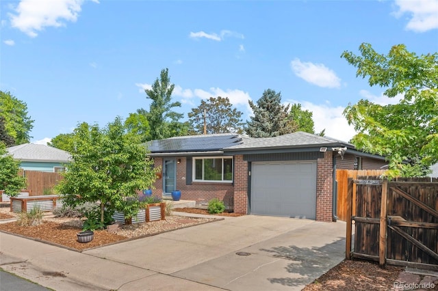 5455 E Iowa Ave, Denver, CO 80222 - view of front of house with brick siding, an attached garage, roof mounted solar panels, and concrete driveway