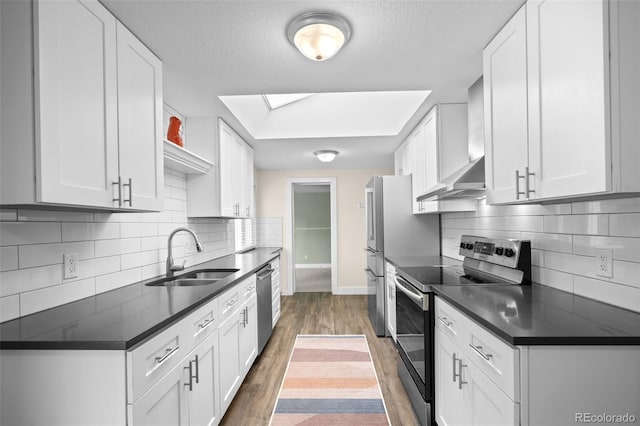 5455 E Iowa Ave, Denver, CO 80222 - kitchen featuring stainless steel appliances, a sink, dark countertops, baseboards, and white cabinetry