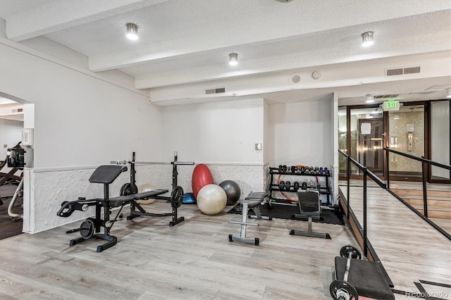 exercise room featuring a textured ceiling and light hardwood / wood-style flooring