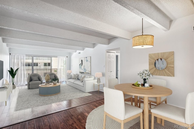 dining room with beam ceiling, hardwood / wood-style floors, and a textured ceiling