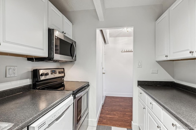 kitchen with beamed ceiling, a textured ceiling, stainless steel appliances, and white cabinetry